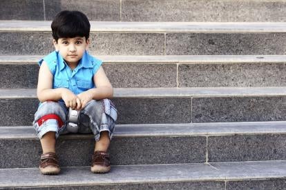 a vulnerable child sitting by himself holding a phone