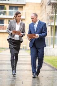 a professional woman and man in a suit walking in discussion 