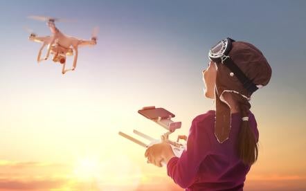 happy young girl controlling a drone or UAV unmanned aerial vehicles 