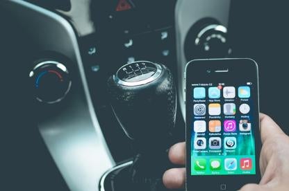 man distracted by smart phone messages while driving