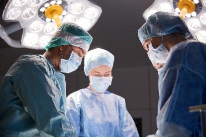 operating room with four doctors and nurses in masks engaged in a procedure