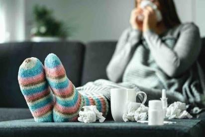 Employee using Sick Leave with fuzzy socks and kleenex