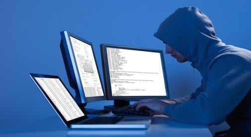 hooded hacker multiple computers and monitors