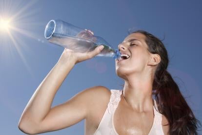 athlectic woman drinking water from a tall clear water bottle