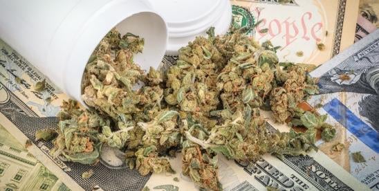 marijuana from a prescription container on a stack of money