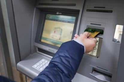 professional inserting either a debit, credit or payroll card in an ATM 