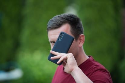 Man holding a mobile phone over his face