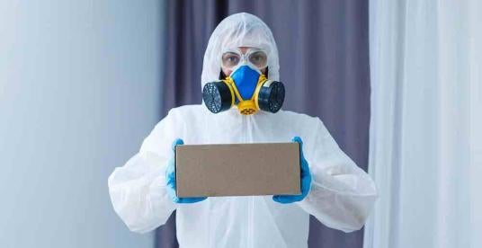 hazmat-suited professional with a box of PFAS items