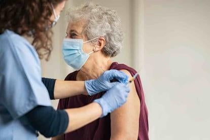 elderly woman getting a vaccine in a nursing home