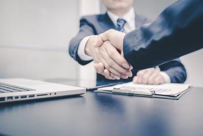 two businessmen shaking hands as sign of completed merger 