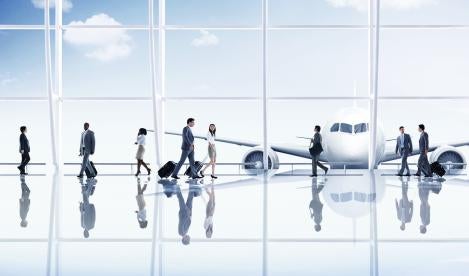 Mostly business travelers in an airport terminal with a plane in the background