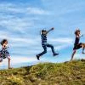 three happy children jumping and playing outdoors