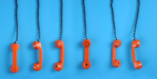 six red retro style phone handsets hanging off the hook