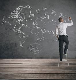 Man standing on a step stool illustrating a life size global network on a chalkboard