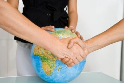 individuals shaking hands and guarding the globe depicting international agreements