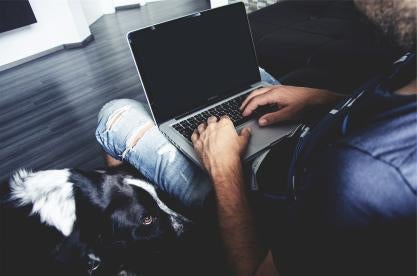 employee working on laptop with dog at home