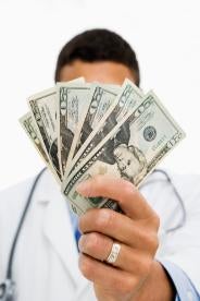 a doctor holding up a stack of bills covering his face